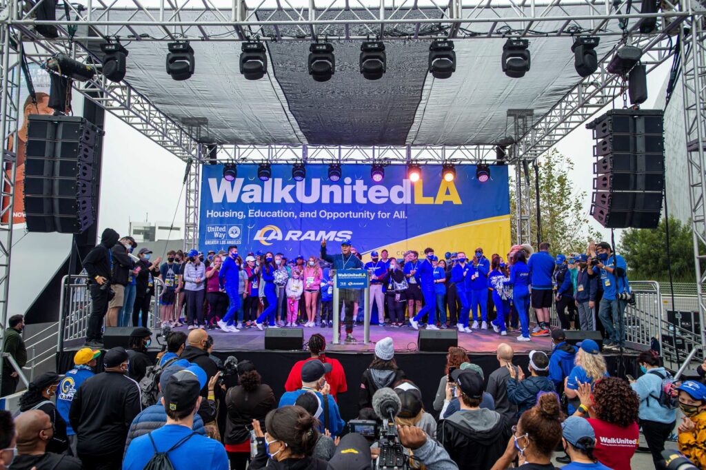 Speaker on WalkUnited stage surrounded by crowd