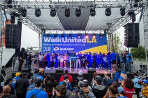 Speaker on WalkUnited stage surrounded by crowd