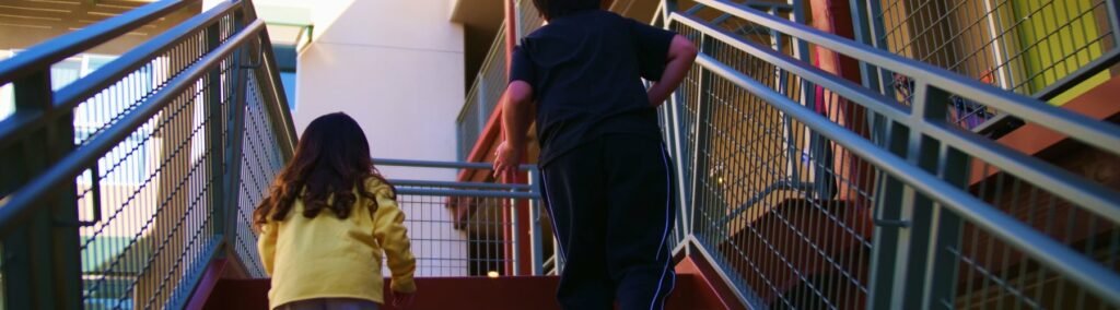 To children running up apartment building outdoor stairs