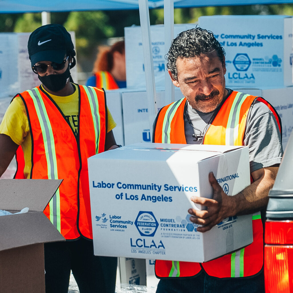 Two people carrying boxes of supplies.