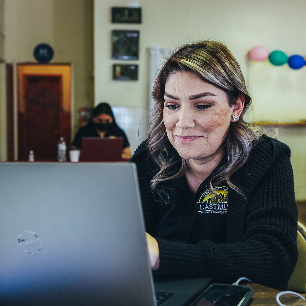 Smiling woman sits in front of a computer.