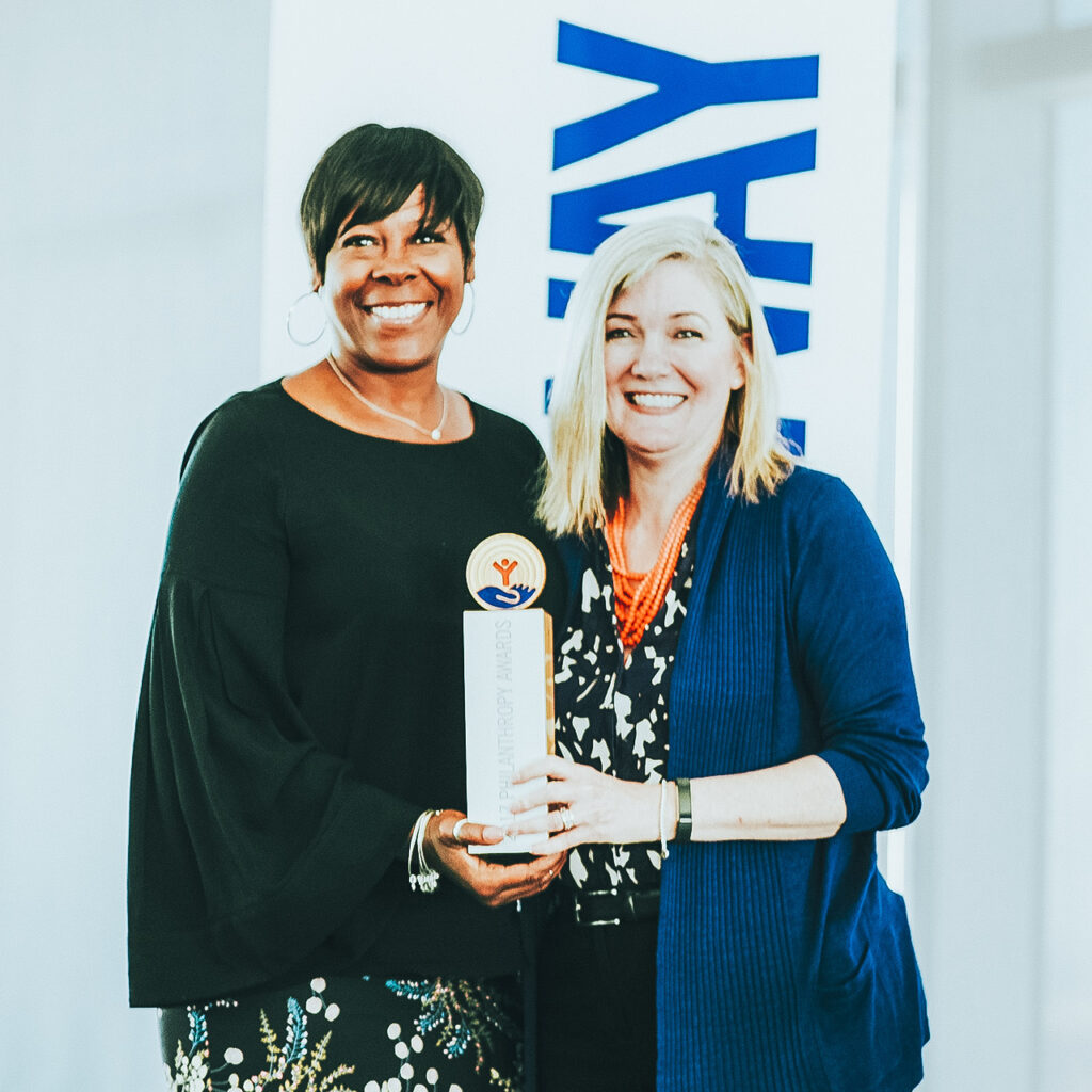 Elise Buik, CEO of United Way of Greater L.A. stands together with a woman of color, both holding an award that says "Philanthropy Awards," given to United Way of Greater L.A.