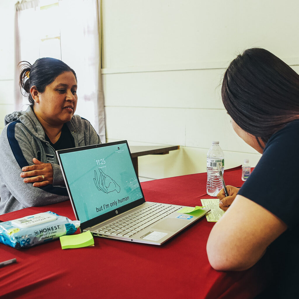 A resident of Greater LA sits with a volunteer to get assistance with taxes. A laptop sits in the center of the photo.