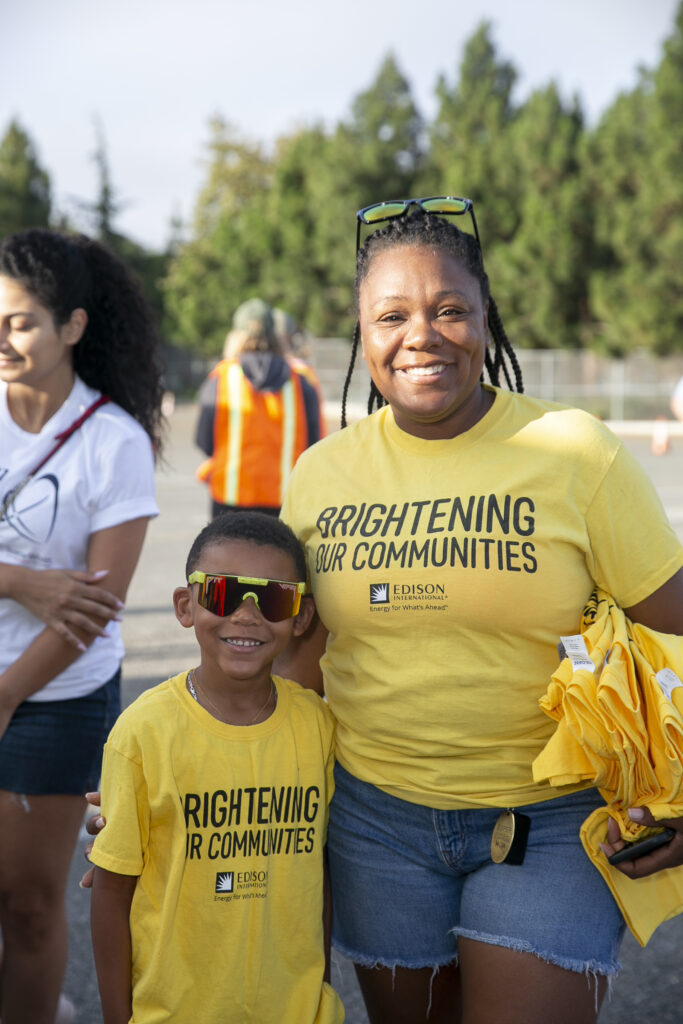 Woman and child smiling in matching yellow shirts at a volunteer event
